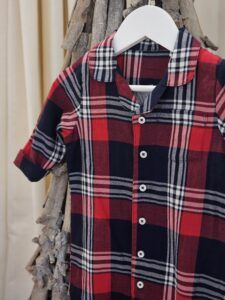 the Larkwood Tartan Romper Pyjamas showing a front view displayed hanging from an ornamental twig tree