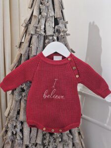 the 'I Believe' Red Christmas Romper displayed hanging from a decorative stick tree