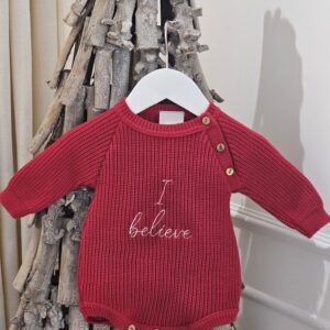 the 'I Believe' Red Christmas Romper displayed hanging from a decorative stick tree