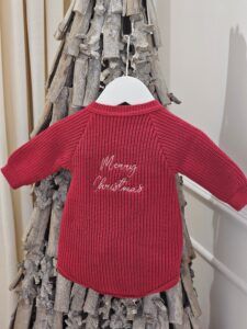 the 'Merry Christmas' Red Romper displayed hanging from a decorative twig tree.