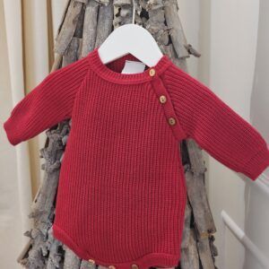 the Dandelion Red Long Sleeve Knitted Romper displayed on a decorative twig tree.
